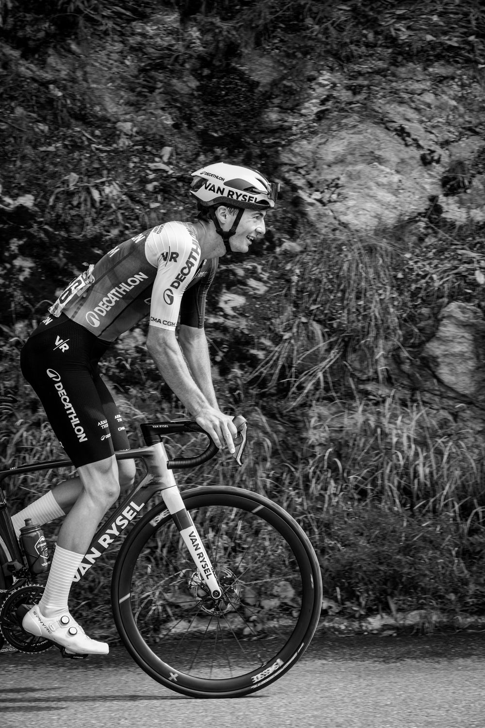 Coureur professionnel grimpant le long d'une paroi rocheuse, en noir et blanc